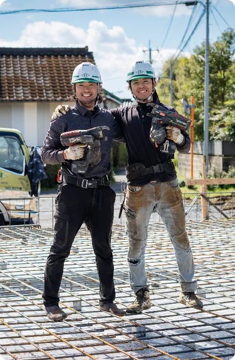 建設現場で笑顔を見せる作業員2人